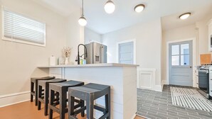 Une cuisine moderne dotée d’un îlot central, de tabourets de bar, d’un réfrigérateur et d’un coin repas.