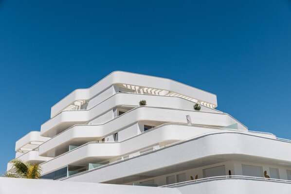 A multi-story building with balconies and a clear blue sky.