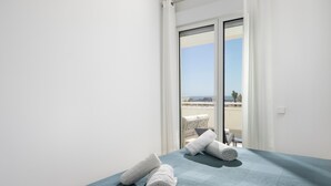 Una habitación con cama, vistas al balcón y una ventana con cortinas.