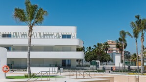 Un edificio moderno con techo plano, ventanas grandes y fachada blanca.
