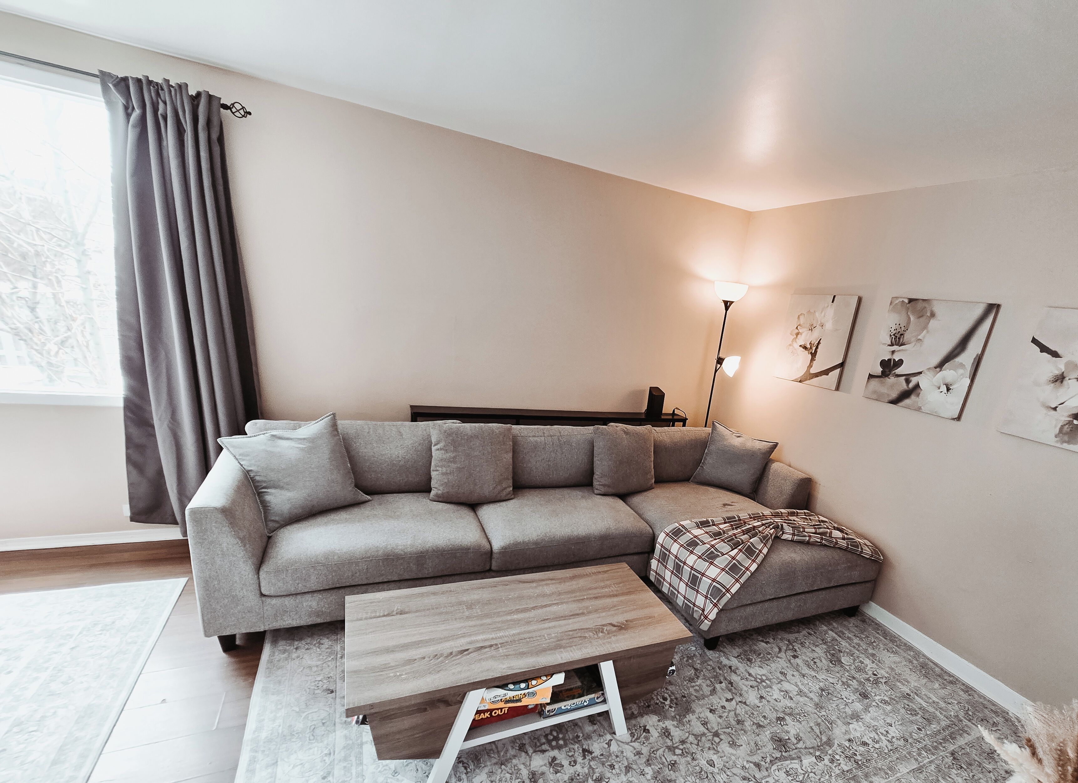 A modern living room with a grey sectional sofa, a small wooden coffee table, and a floor lamp.