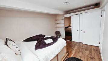 A bedroom with a bed, a chair, a wardrobe, and a small closet.