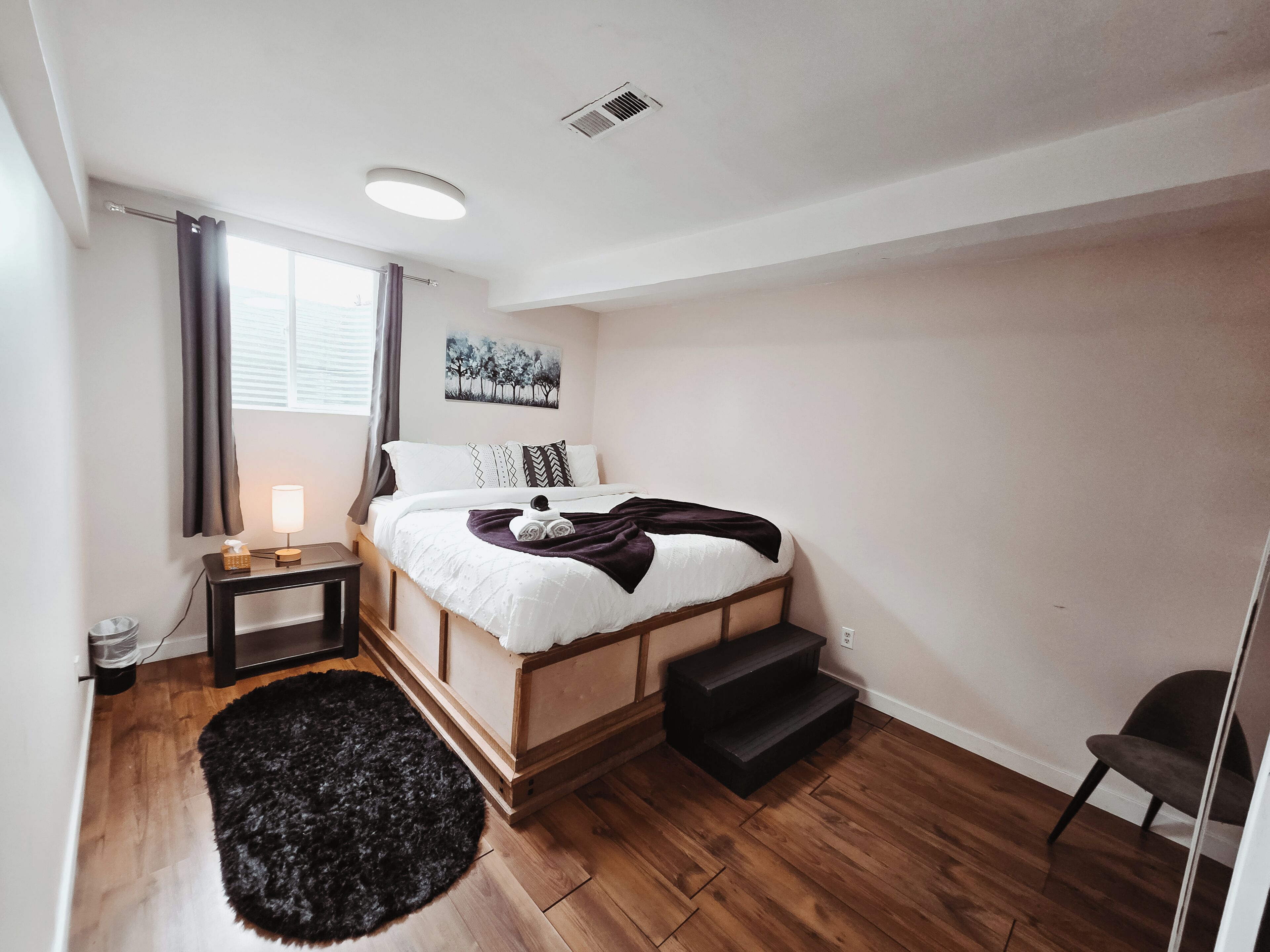 Une chambre à coucher avec un lit, une table de chevet, une lampe et un tapis noir.