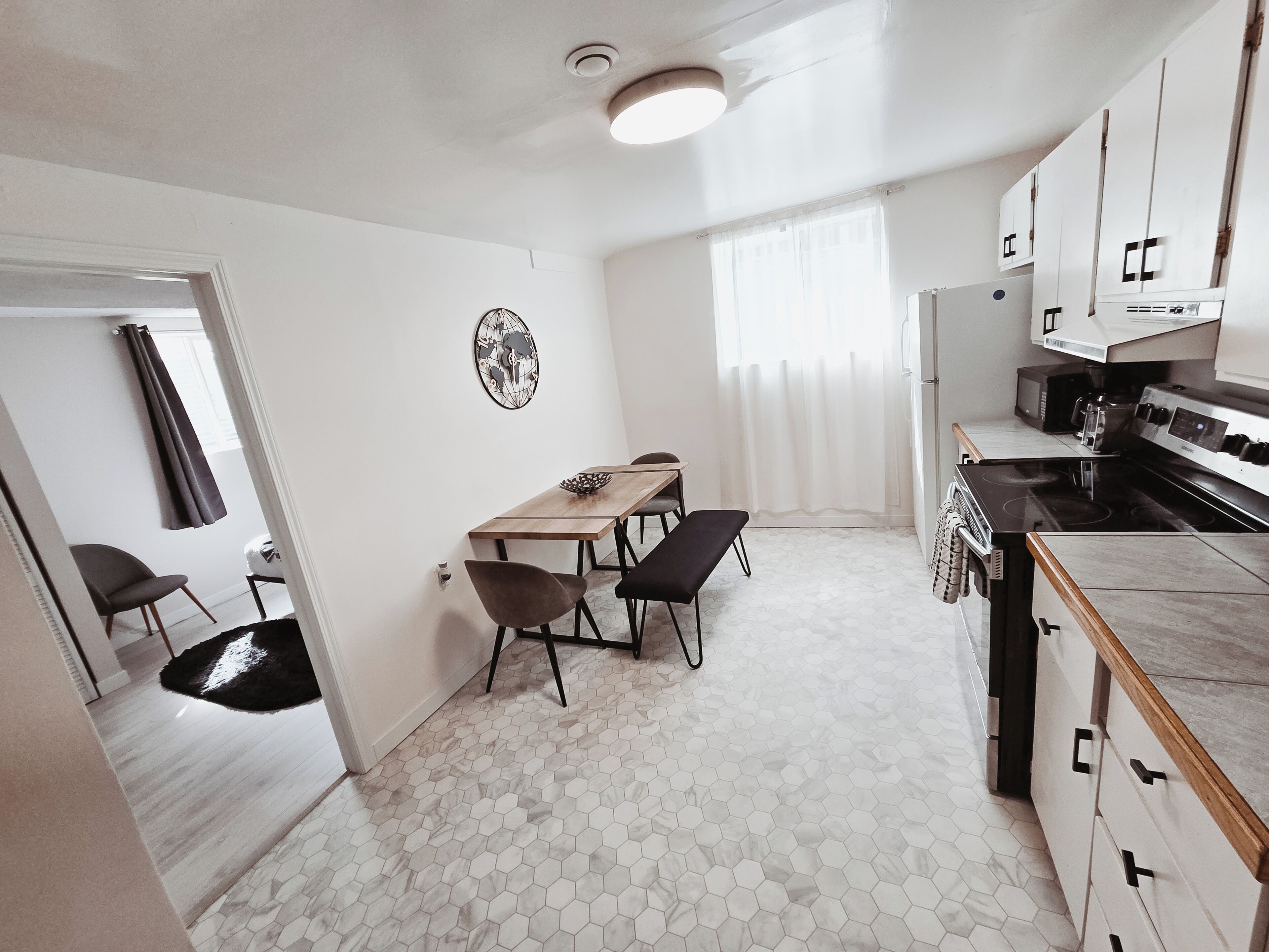 Una cocina compacta con una mesa de comedor, sillas, estufa y armarios.