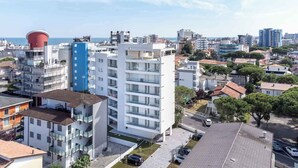En moderne lejlighedskompleks med flere etager, altaner og parkeringsplads.