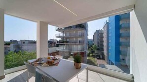 En moderne lejlighed med balkon, store vinduer og spiseområde med et bord dækket til to.