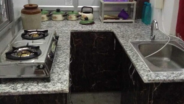 A compact kitchen with a gas stove, a sink, and a small countertop. - Accommodation In Prayagraj (Prayagraj)