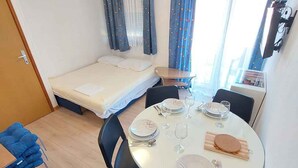 Une chambre d’hôtel compacte comprenant un lit, une petite table à manger pour deux personnes et un coin cuisine.