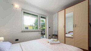 Ein Schlafzimmer mit Bett, Kleiderschrank, Fenster und Stuhl.