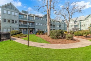 A multi-story residential building with a central courtyard, balconies, and a well-maintained lawn.
