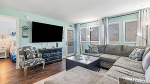 Una sala de estar con televisor, sofá, sillón y una mesa de centro.