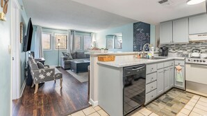 Una cocina moderna con una isla central, electrodomésticos integrados y una zona de comedor con sofá y mesa.