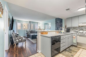 Una cocina moderna con una isla central, electrodomésticos integrados y una zona de comedor con sofá y mesa.