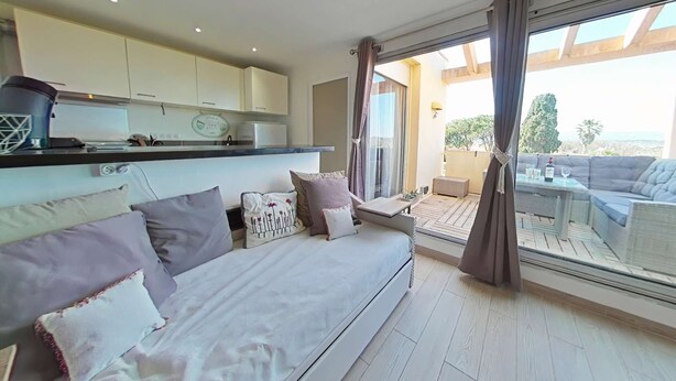 A modern living room with a sofa, a dining table, and a view of the outdoors.