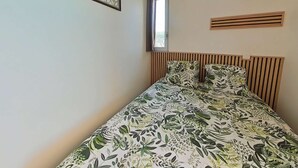 A bedroom with a bed, a window, and a decorative wall piece.