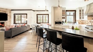 Una cuina moderna amb una illa central, tamboretes de bar i una zona de menjador amb un sofà i cadires.