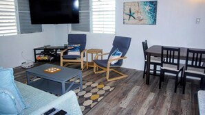 A living room with a flat-screen TV, a sofa, a coffee table, a dining table with chairs, and a starfish artwork on the wall. - Spacious 6-bedroom villa in gorgeous Luquillo with WiFi, AC (Luquillo)