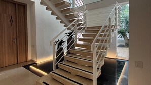 Una escalera moderna con barandillas de vidrio y detalles de madera que conduce a un segundo piso.