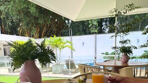 Una escena de desayuno con una mesa, platos de comida, un vaso de zumo de naranja y un bol de cereales.