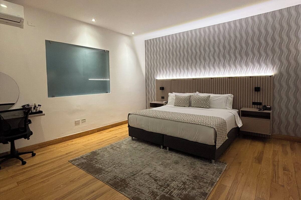 Een moderne slaapkamer met een groot bed, een bureau en een stoel.