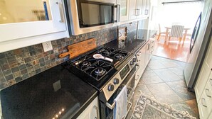 Une cuisine moderne équipée d’une cuisinière à gaz, d’un four, d’un four à micro-ondes et de meubles de rangement en acier inoxydable.