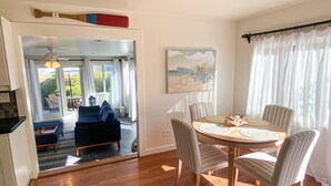 Un coin repas avec une table ronde et des chaises, un canapé et une vue sur l’extérieur grâce à une porte vitrée.