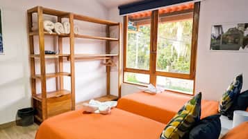 Una habitación con una cama, una estantería de madera y una ventana con vistas a zonas verdes.