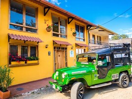 Un Jeep verde estacionado frente a un edificio amarillo con puerta y ventanas de madera.