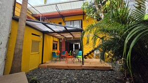 A yellow building with a covered patio area, outdoor seating, and a staircase leading to an upper level. - Hotel La Caracola Salento (Salento)