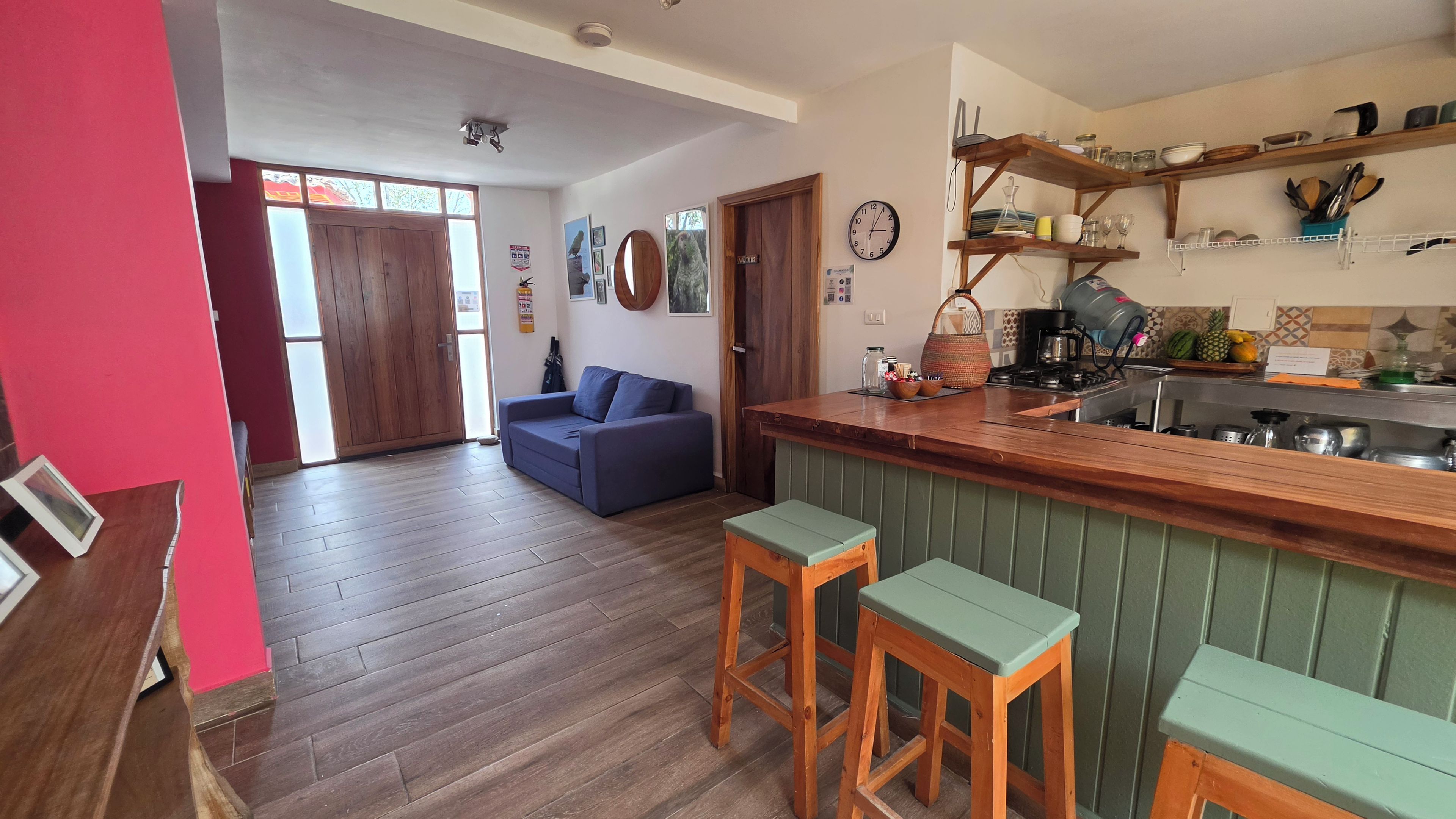 A kitchen with wooden bar stools, a blue sofa, and a dining table.