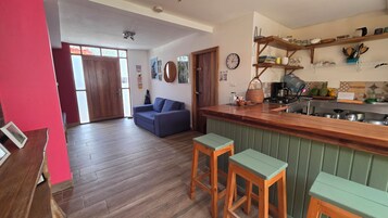 Una cocina con taburetes de madera, un sofá azul y una mesa de comedor.