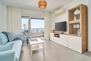 En moderne stue med sofa, sofabord, fjernsyn og et glaskab.