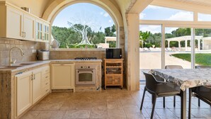 A kitchen with an archway, a built-in oven, a microwave, and a dining area with outdoor seating. - Holiday Home 'Buontempo' with Private Pool, Wi-Fi and Air Conditioning (Francavilla Fontana)