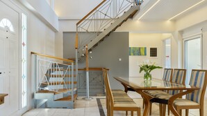 A modern interior with a staircase, dining area, and a view of the outdoors.
