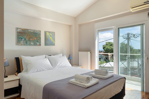 Une chambre à coucher avec un lit, deux tableaux, une table de chevet, une lampe, un radiateur et un balcon avec vue.