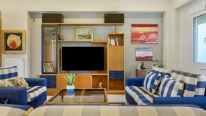 A living room with a large flat-screen TV, two sofas, a coffee table, and a bookshelf.