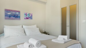 Habitación de hotel con cama, dos cuadros, un armario y toallas sobre la cama.