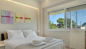 A hotel room with a bed, white linens, a window with a view, and three abstract paintings on the wall. - Ground Floor Bedroom 2 with Shared Terrace, Wi-Fi, and Air Conditioning (????????S)