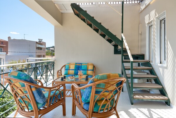 A balcony with wicker furniture, a table, and a staircase.