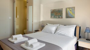 A hotel room with a bed, towels, a nightstand, a lamp, and two paintings on the wall. - First Floor Bedroom 3 with Shared Terrace, Wi-Fi, and Air Conditioning (????????S)
