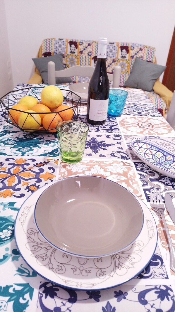 Uma mesa de jantar com uma tigela, uma garrafa de vinho e um copo de água.