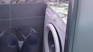 A laundry area with a washing machine and a large fan.