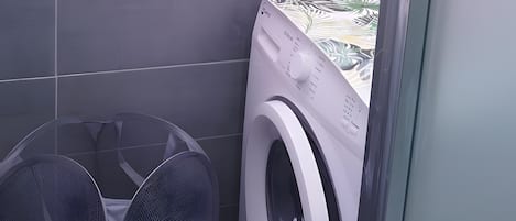 Un área de lavandería con lavadora y un ventilador grande.
