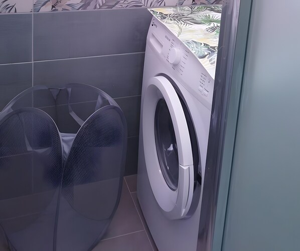 Ett utrymme för tvätt med en tvättmaskin och en stor fläkt.