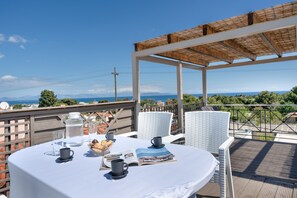 A covered outdoor seating area with a table set for two, a book, and a bowl of snacks. - Room 'Lower Level 6' with Shared Terrace, Wi-Fi & Air Conditioning (????????S)