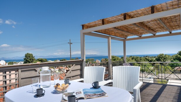 Un espacio al aire libre cubierto con una mesa para dos, un libro y un tazón de bocadillos.