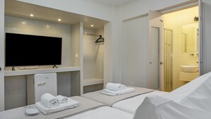 Habitación de hotel con televisión, dos camas, ducha y lavamanos.