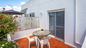 A patio with a table and chairs, a sliding glass door, and a white fence.