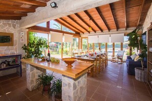 A spacious kitchen with a central island, stone walls, wooden beams, and large windows. - Cottage 'Coscoix - Hermosa Casa De Campo' with Private Pool, Private Terrace and Wi-Fi (Santa Margalida)
