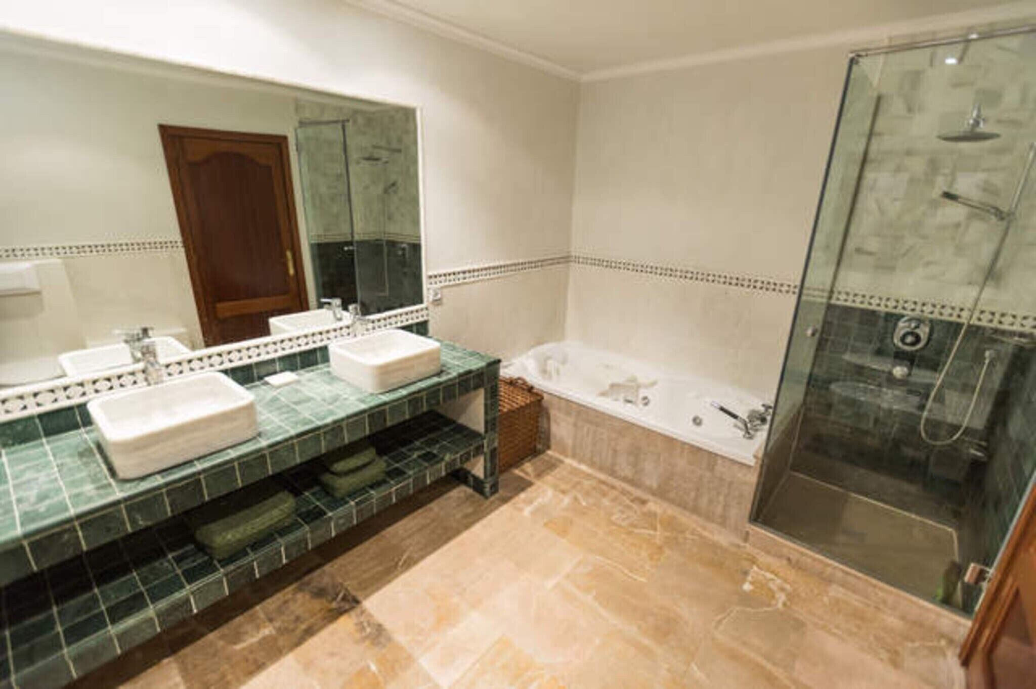 Un baño con dos lavamanos, una bañera y una ducha con mampara de vidrio.